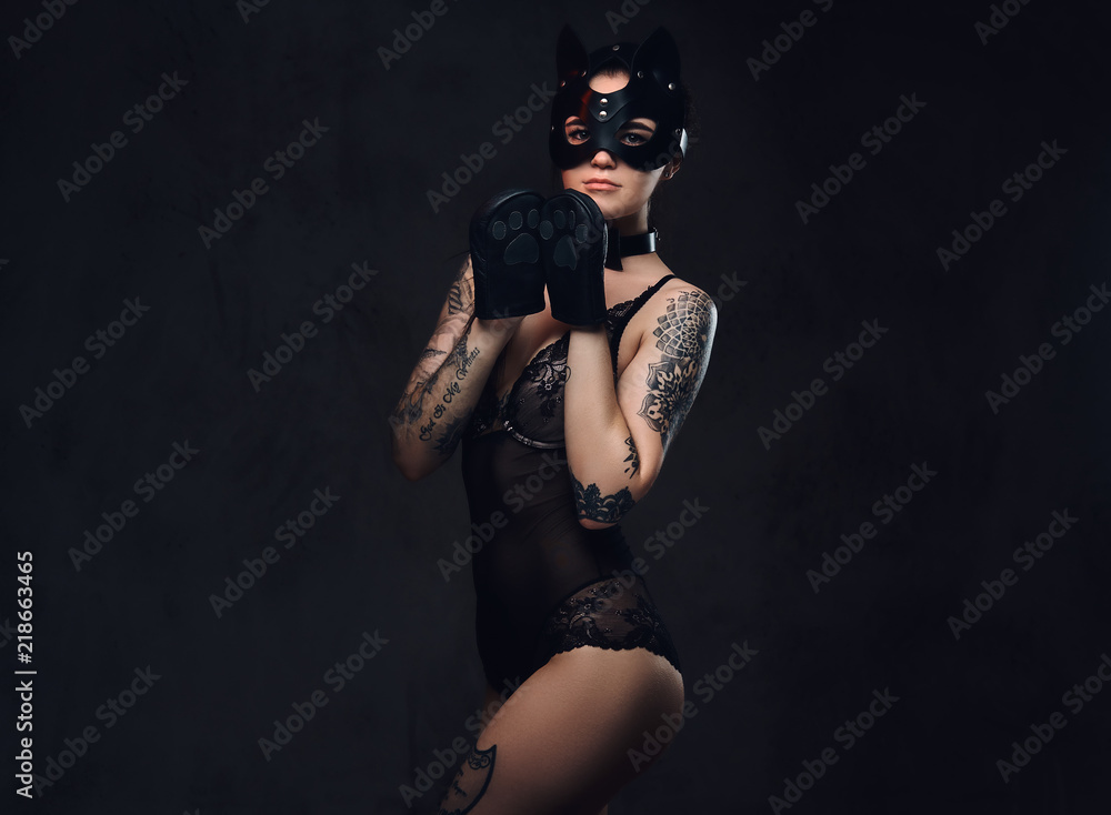 Sexy woman wearing black lingerie in BDSM cat leather mask and accessories posing on dark background. Sexy woman wearing black lingerie in BDSM cat leather mask and accessories posing on dark background.