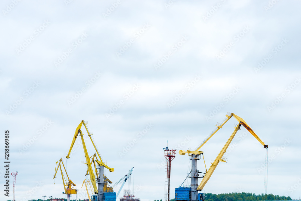 Cranes are working at the sea port on cloudy sky background Cranes are working at the sea port on cloudy sky background