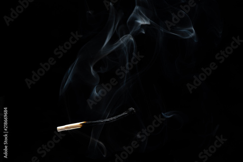 Burnt matchstick with smoke on black background