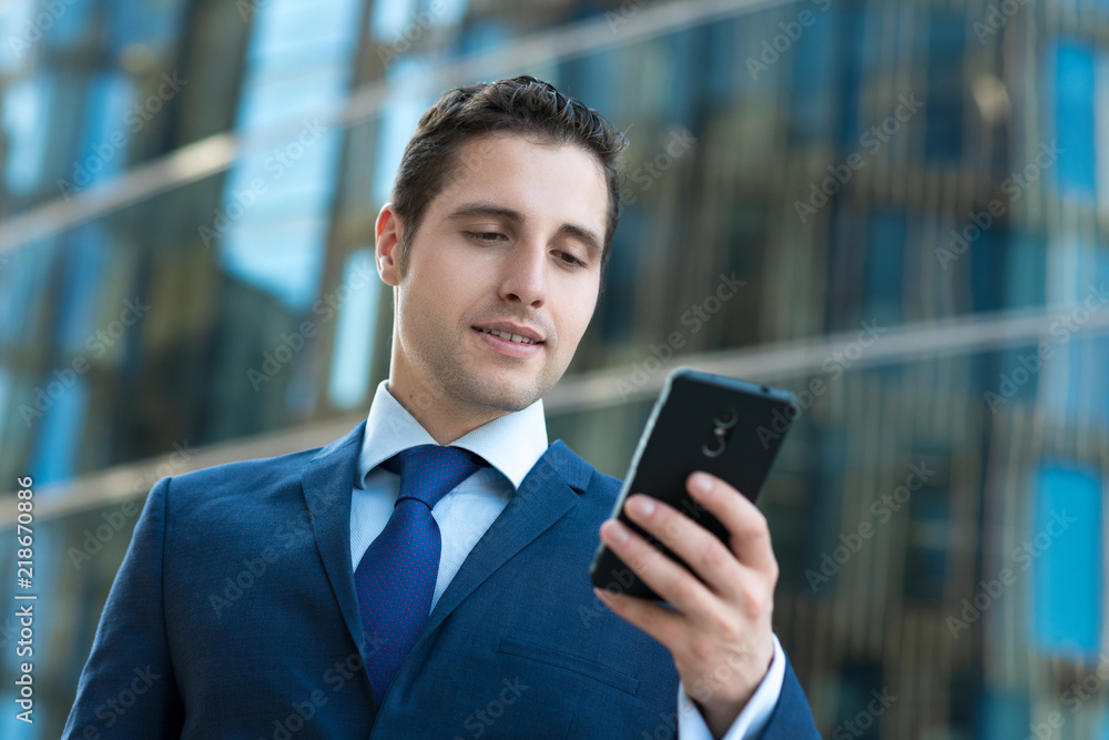 Handsome business man in suit texting message in front od modern building Handsome business man in suit texting message in front od modern building