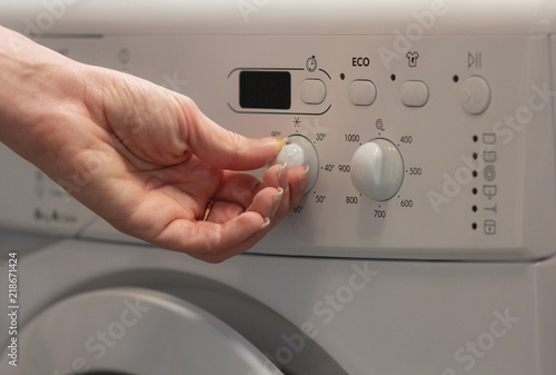 The girl switches the temperature in the washing machine