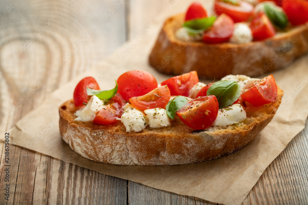 Bruschetta with tomatoes, mozzarella cheese and basil on a old rustic table. Traditional italian appetizer or snack, antipasto. with copy space