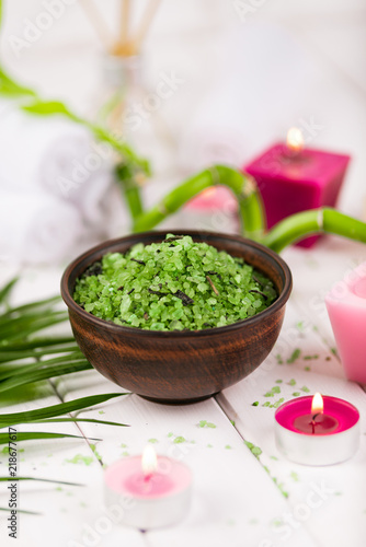 Spa. Green herbal spirulina salt in ceramic bowl, spa towels, pink scented candle and bamboo