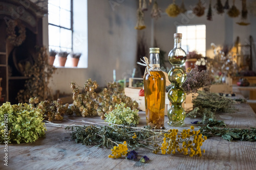 Two bottles with oil on a table with dried herbs and flowers