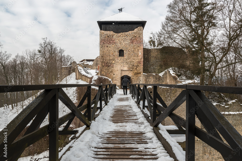 Medieval castle of Lukov, Czech Republic during winter morning with wooden bridge and a person on it and covered with snow. Lukov, Czech Republic