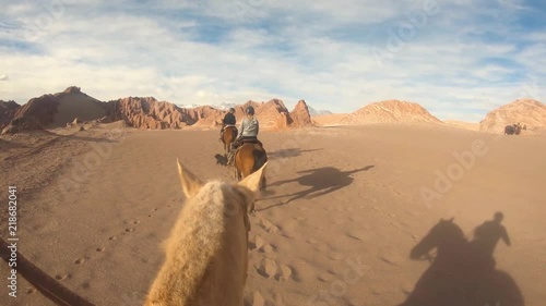 People riding horse slow mo at the San Pedro De Atacama desert Chile. Three person in a line going forward one behind filming
