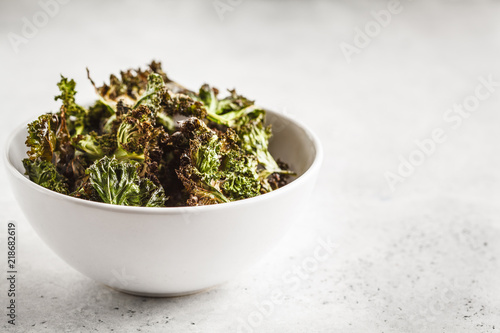 Kale chips in a white bowl on white background. Clean eating concept.