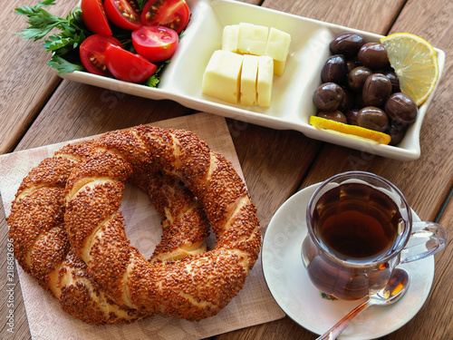 turkish bagel on wooden table, tea and breakfast plate. Tomatoes, cheese, olives photo