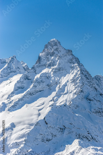 Mt. Belalakaya summit against clear blue sky in winter sunny day. Dombay ski resort, Western Caucasus, Russia.