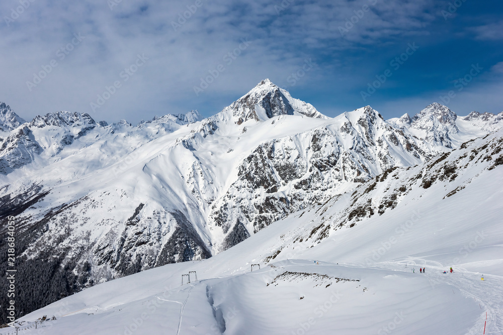 Ski slope with Mt. Semenov-Bashi on the horizon in winter sunny day. Dombay ski resort, Western Caucasus, Russia.