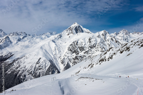 Ski slope with Mt. Semenov-Bashi on the horizon in winter sunny day. Dombay ski resort, Western Caucasus, Russia.