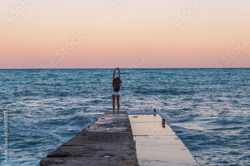 Relaxed young woman on a pier on the background of the sea