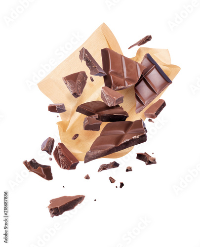 Pieces of crushed chocolate are fly out of a paper wrapper, isolated on white background