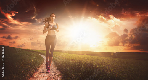 Fit determined woman running against sky at sunset