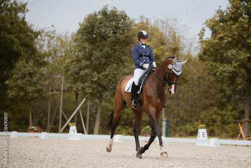 Reiterin trabt mit ihrem Pferd über den Reitplatz während einer Prüfung auf einem Turnier in der Dressur
