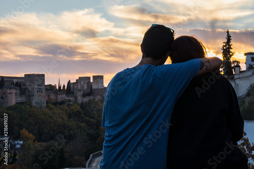 hugging couple watching the beautiful sunset over the Alhambra, from Sacromonte, Granada, Spain