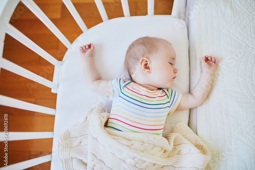 Baby girl sleeping in co-sleeper crib photo