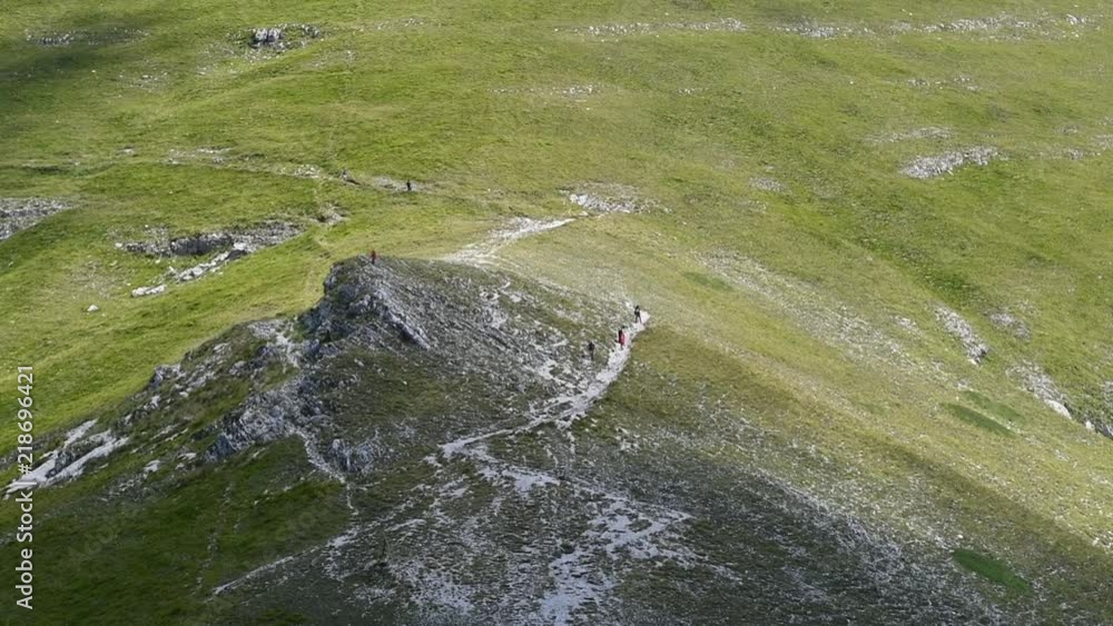People walking and climbing mountain on path, long shot and cloud shadow on green field People walking and climbing mountain on path, long shot and cloud shadow on green field