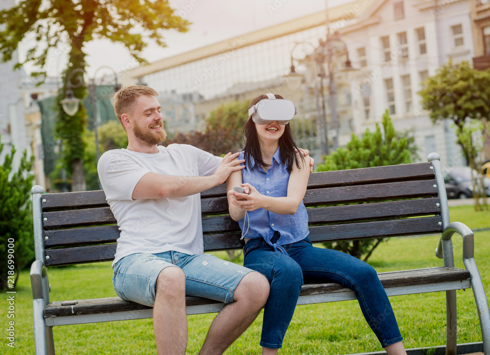 A young couple plays a game using virtual reality glasses on the street. A young couple plays a game using virtual reality glasses on the street.