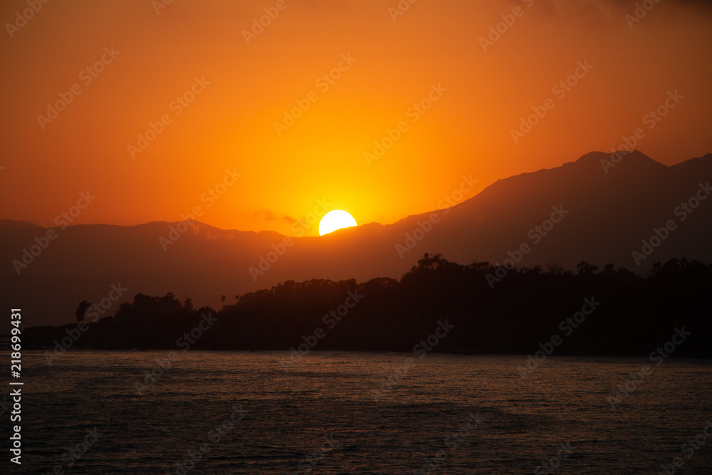 Naklejka premium Sunset, Santa Barbara, California, Rincon Beach, sea, pacific ocean, orange, mountains, sun behind mountains