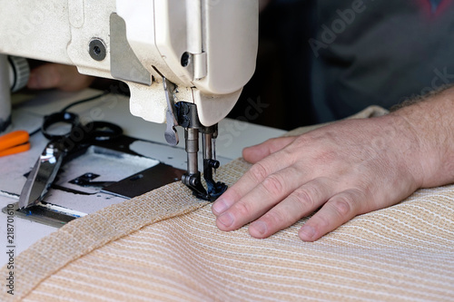 Men's hands sew bags on the sewing machine. Sewing bags for rice and sugar. Hired labor. Professional seamstress. Man seamstress. Men's hands behind sewing leather. photo