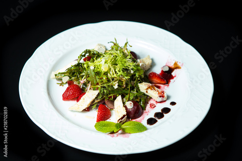 Strawberry tomato salad with feta cheese, olive oil on black background