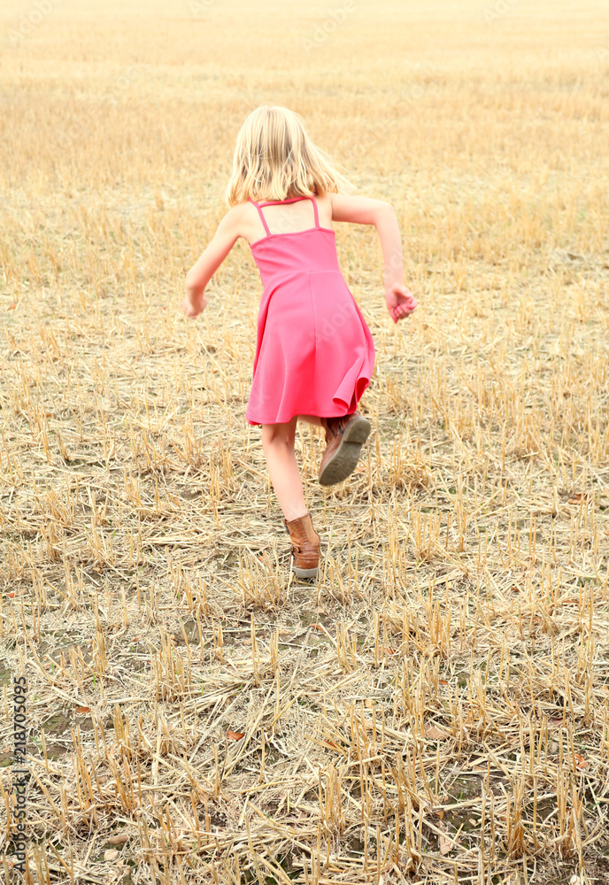 girl running across a cut corn field girl running across a cut corn field