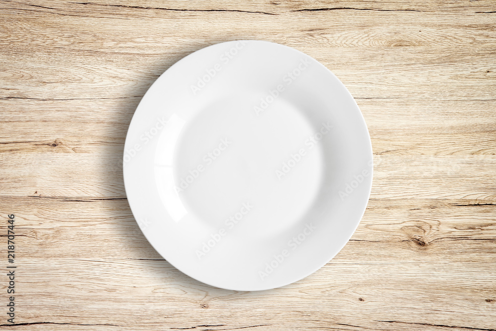 Top view of empty white food plate on a wood background. Top view of empty white food plate on a wood background.