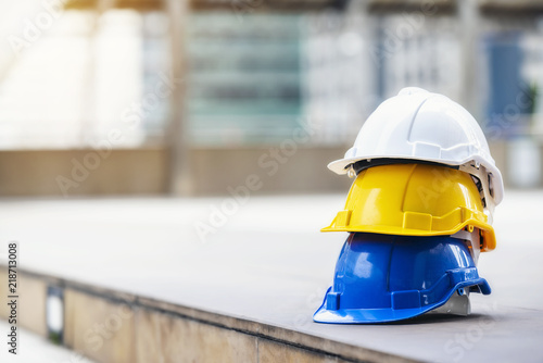 white, yellow and blue hard safety helmet hat for safety project of workman as engineer or worker, on concrete floor on city.