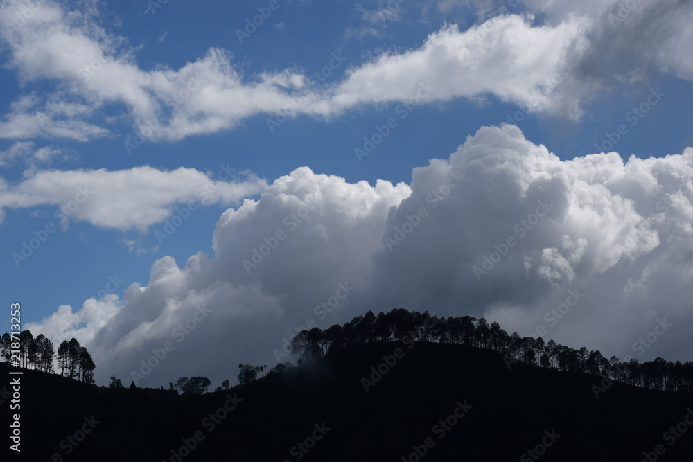 white clouds and blue sky during daytime abstract clouds above mountains filled with trees