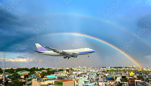 Passenger plane flying through the urban area with sunrays and rainbow in the sky prepared landing airport. Business trip, commercial plane, travel