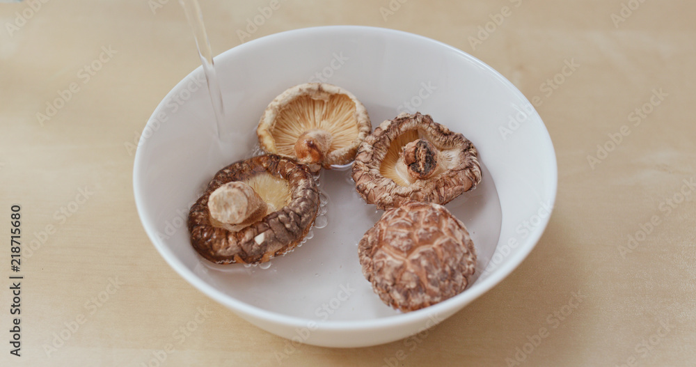 Adding water into white bowl with chinese dry mushroom Adding water into white bowl with chinese dry mushroom