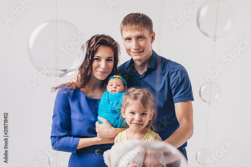 Family portrait on white background: newborn baby surrounded by man, woman and girl photo