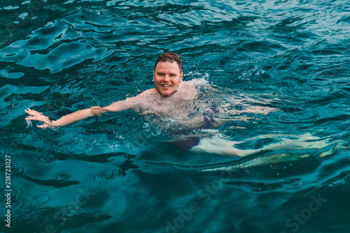 man swimming in blue transparent sea water