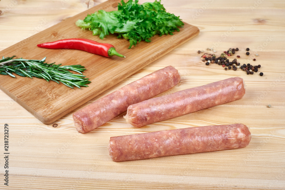 Raw sausages with vegetables and spices on wooden background Raw sausages with vegetables and spices on wooden background