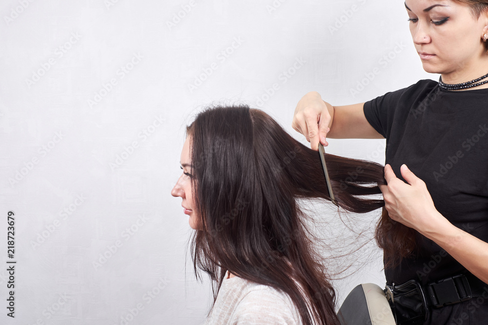 Fototapeta premium Female hairdresser makes a haircut for a woman closeup in beauty salon