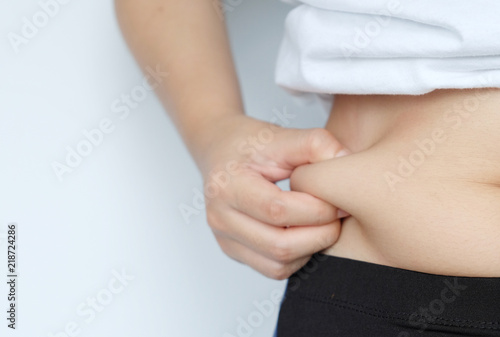 Side of woman hand catching fat body belly paunch , diabetic risk factor .