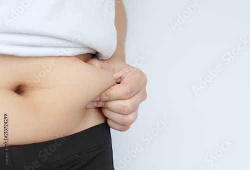 Side of woman hand catching fat body belly paunch , diabetic risk factor .