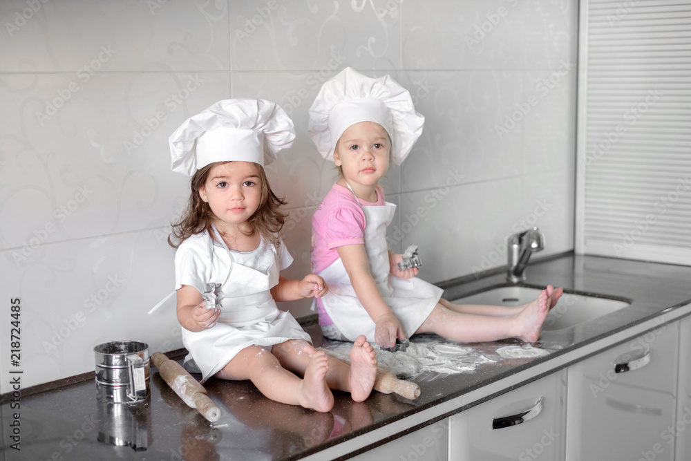 Two Little girl preparing cookies in kitchen at home Two Little girl preparing cookies in kitchen at home