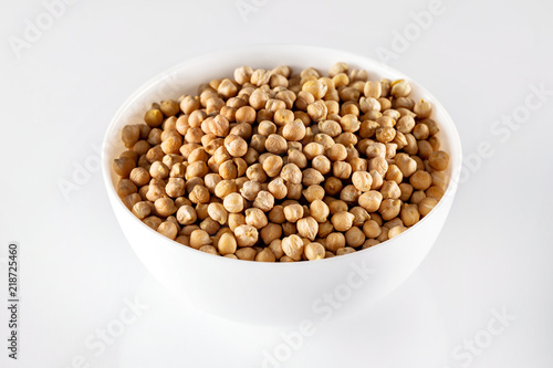 Closeup bowl of uncooked chickpeas isolated at white background.