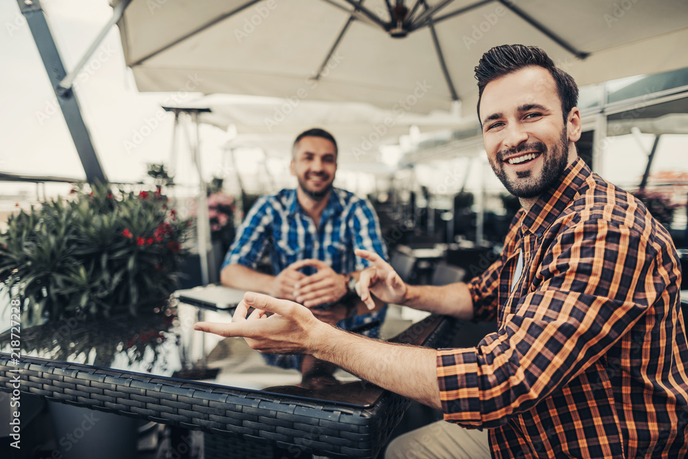 Having fun. Smiling guys spending time at outdoor cafe. Focus on laughing gentleman with hand gestures Having fun. Smiling guys spending time at outdoor cafe. Focus on laughing gentleman with hand gestures