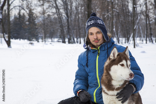 Christmas happy teenager boy playing with white Husky dog in winter day, dog and child on snow