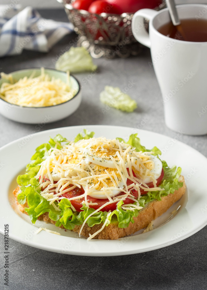 White bread sandwich with lettuce, tomato, boiled egg and grated cheese. Delicious lunch, healthy Breakfast on grey background White bread sandwich with lettuce, tomato, boiled egg and grated cheese. Delicious lunch, healthy Breakfast on grey background