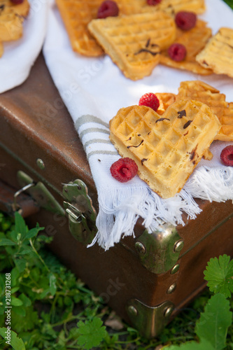 Sweet heart shaped waffles with raspberries for dessert outdoor picnic in the garden.