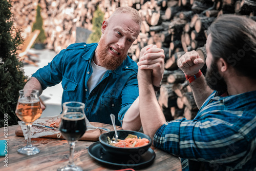 Arm wrestling. Bearded men having much fun while arm wrestling and drinking beer together