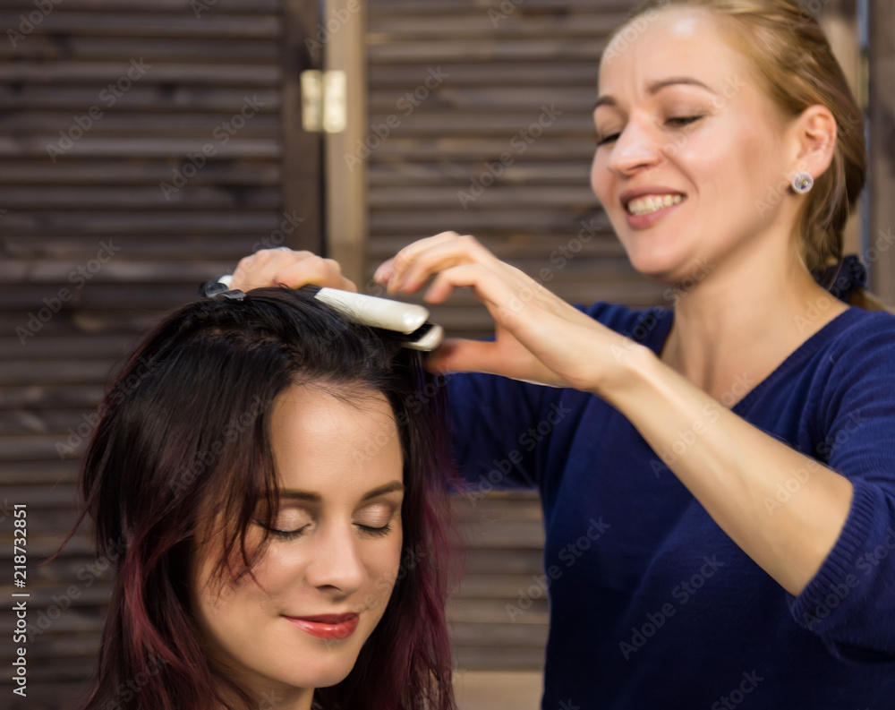 Naklejka premium elegant woman in beauty saloon. Hairdresser does coiffure in the form of big curl. Concept wedding hairstyle