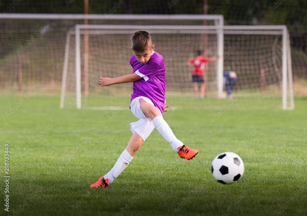 Boy kicking football on the sports field Boy kicking football on the sports field