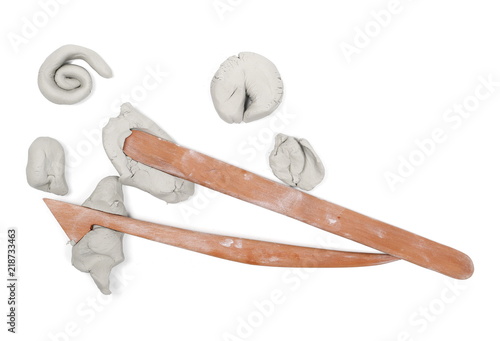 Grey modelling clay lumps, abstract shapes with wooden art spatulas isolated on white background, top view