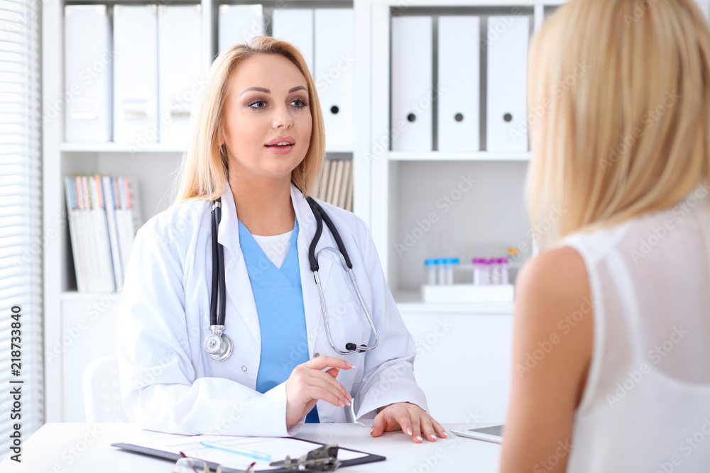 Doctor and patient discussing something while sitting at the table at hospital. Medicine and health care concept Doctor and patient discussing something while sitting at the table at hospital. Medicine and health care concept