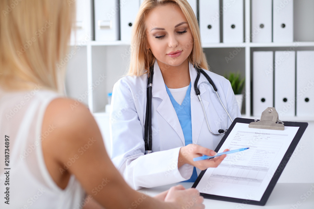 Doctor and patient discussing something while sitting at the table at hospital. Medicine and health care concept Doctor and patient discussing something while sitting at the table at hospital. Medicine and health care concept